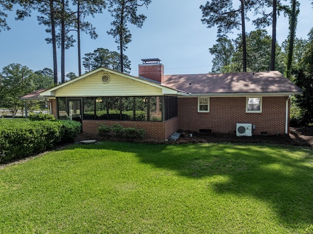 back of property featuring a lawn, a chimney, brick siding, and a sunroom