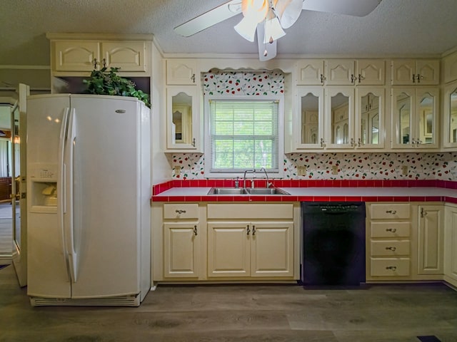 kitchen with a textured ceiling, a sink, white refrigerator with ice dispenser, tile countertops, and black dishwasher