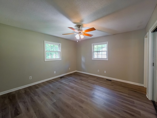 unfurnished bedroom featuring a textured ceiling, visible vents, dark wood-style floors, and baseboards