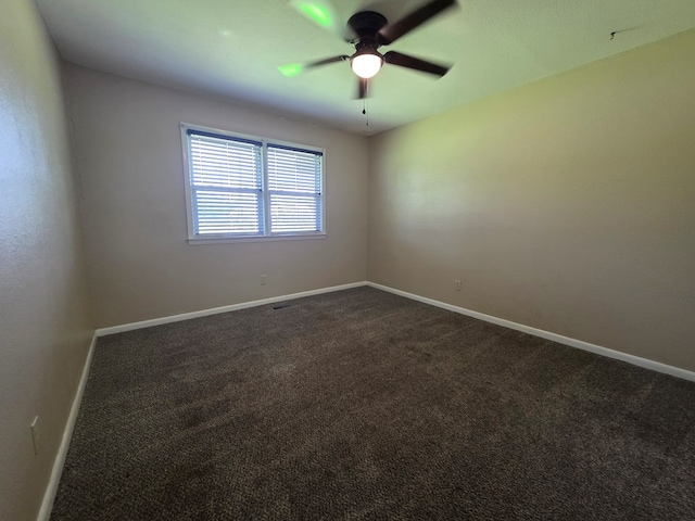 unfurnished room featuring baseboards, a ceiling fan, and dark carpet
