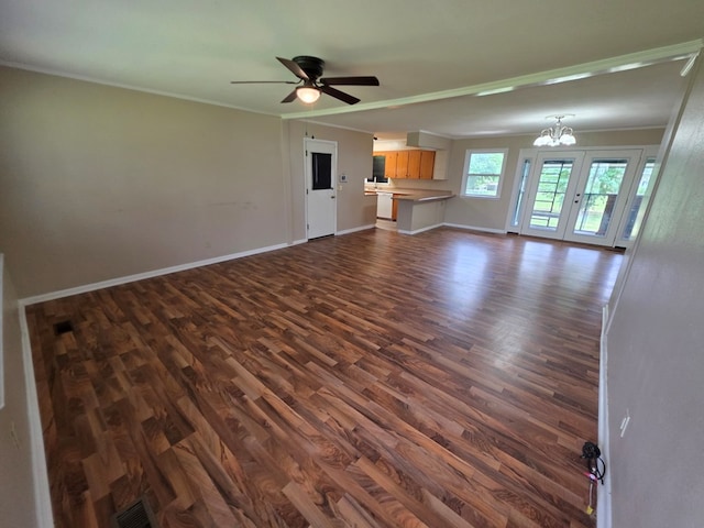 unfurnished living room featuring crown molding, visible vents, baseboards, dark wood-style floors, and ceiling fan with notable chandelier