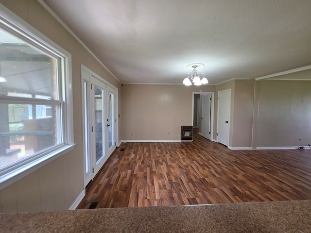 spare room with baseboards, ornamental molding, wood finished floors, and a chandelier