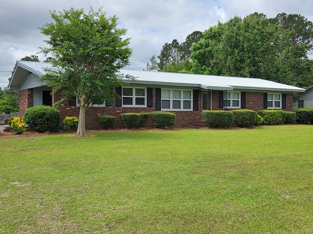 ranch-style home featuring brick siding, metal roof, and a front yard
