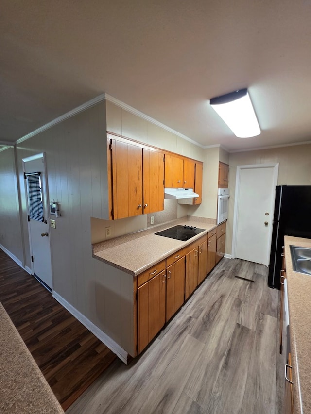 kitchen with crown molding, black appliances, wood finished floors, and under cabinet range hood