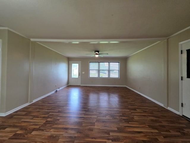 spare room with crown molding, dark wood finished floors, ceiling fan, and baseboards