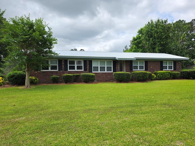 single story home featuring a front yard, metal roof, and brick siding