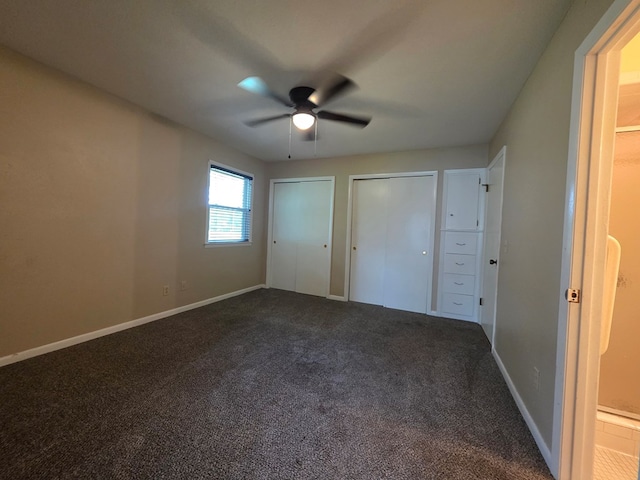 unfurnished bedroom featuring dark colored carpet, multiple closets, ceiling fan, and baseboards