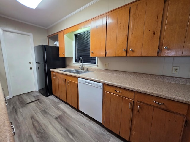 kitchen with a sink, dishwasher, light wood-style flooring, freestanding refrigerator, and ornamental molding