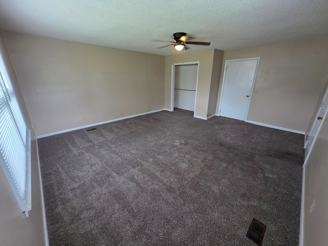 unfurnished bedroom with ceiling fan, a textured ceiling, visible vents, baseboards, and dark carpet