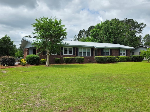ranch-style home featuring brick siding, metal roof, and a front lawn