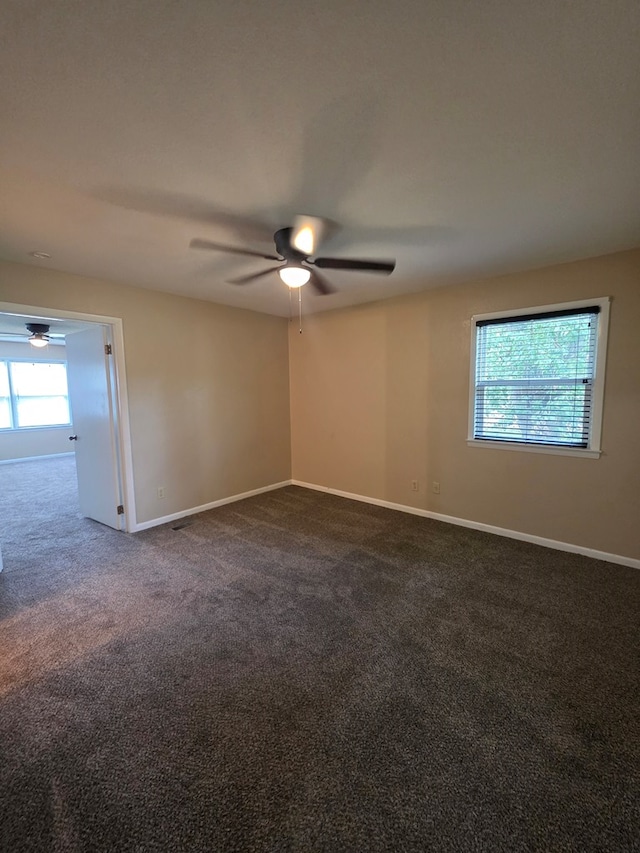 empty room with dark carpet, baseboards, and ceiling fan