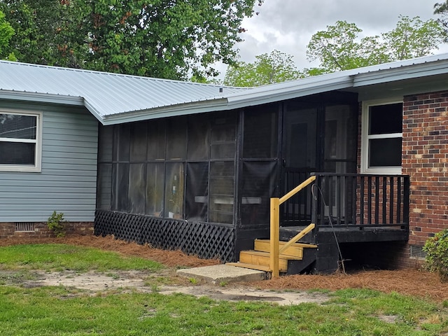 rear view of property featuring crawl space, metal roof, and a sunroom
