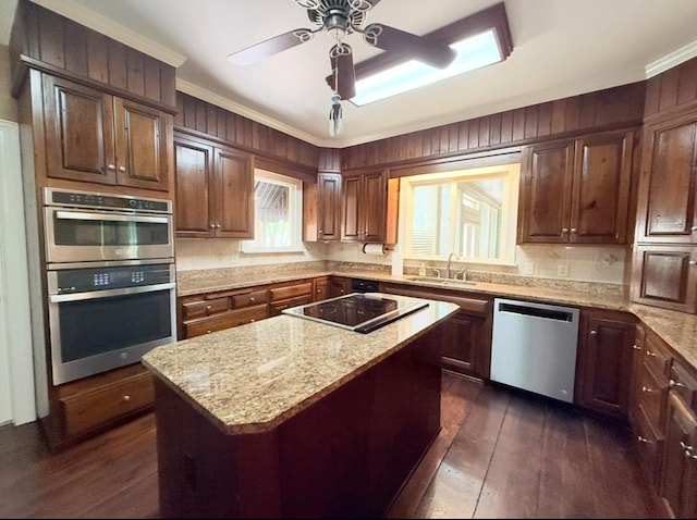 302 W 26th St, Tifton, GA 31794 - kitchen with stainless steel appliances, dark wood finished floors, crown molding, light stone counters, and a center island
