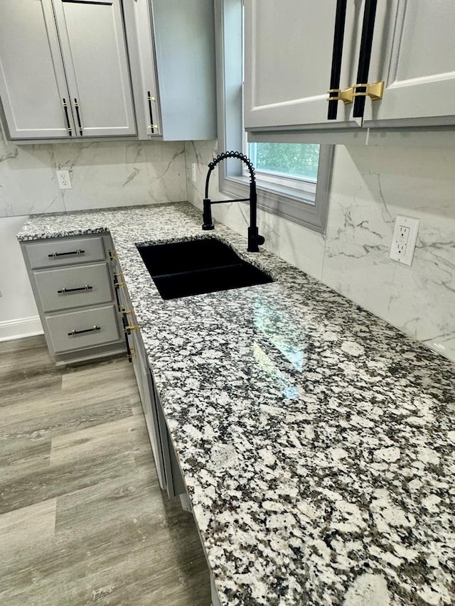 702 N Livingston St, Sylvester, GA 31791 - kitchen with gray cabinetry, light stone counters, light wood-style flooring, and backsplash