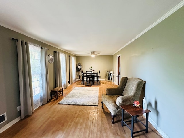 sitting room featuring baseboards, wood finished floors, and crown molding