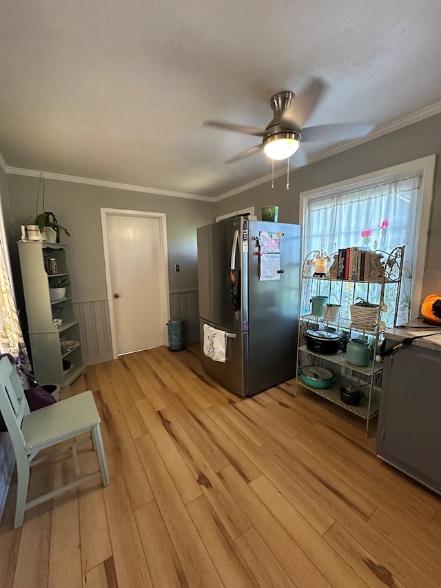 kitchen featuring ceiling fan, light wood-type flooring, a wainscoted wall, ornamental molding, and freestanding refrigerator