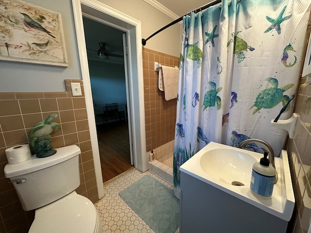 bathroom featuring tile walls, a shower stall, vanity, toilet, and a wainscoted wall