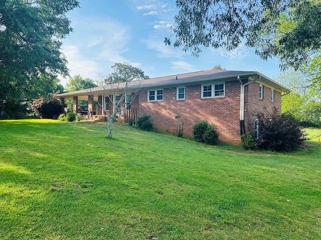 rear view of house featuring brick siding and a lawn