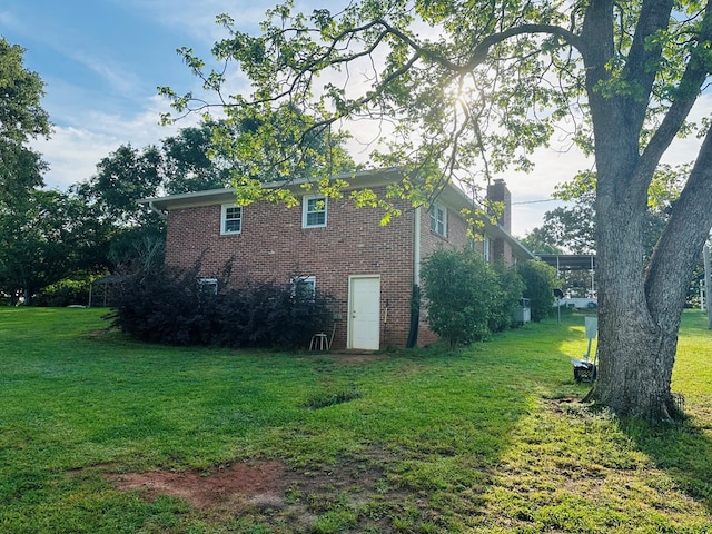 view of property exterior featuring a lawn, a chimney, and brick siding
