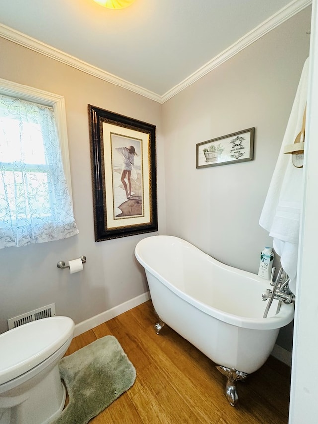 bathroom featuring wood finished floors, a freestanding tub, toilet, visible vents, and crown molding