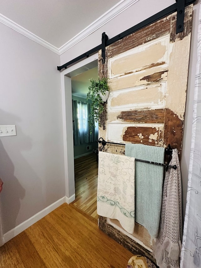 corridor with baseboards, a barn door, wood finished floors, and ornamental molding