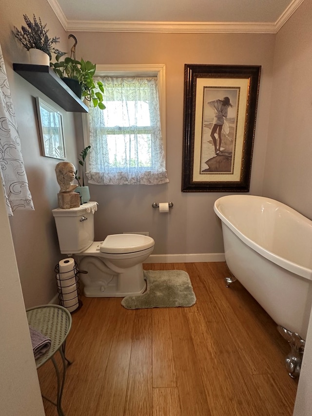 bathroom featuring wood finished floors, toilet, crown molding, and a soaking tub