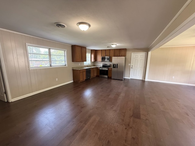 2411 Davis Ave, Tifton, GA 31794 - kitchen featuring stainless steel appliances, open floor plan, dark wood-style flooring, brown cabinets, and wood walls