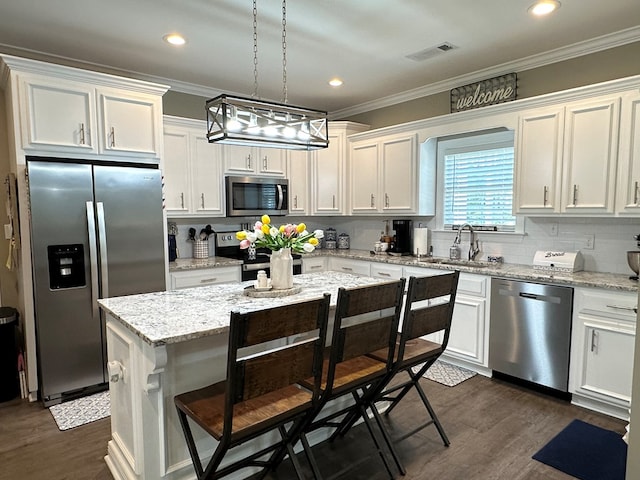 kitchen featuring white cabinets, stainless steel appliances, ornamental molding, and a sink