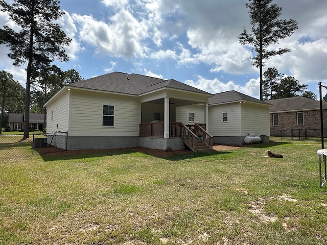 rear view of house with fence, roof with shingles, stairway, covered porch, and a yard