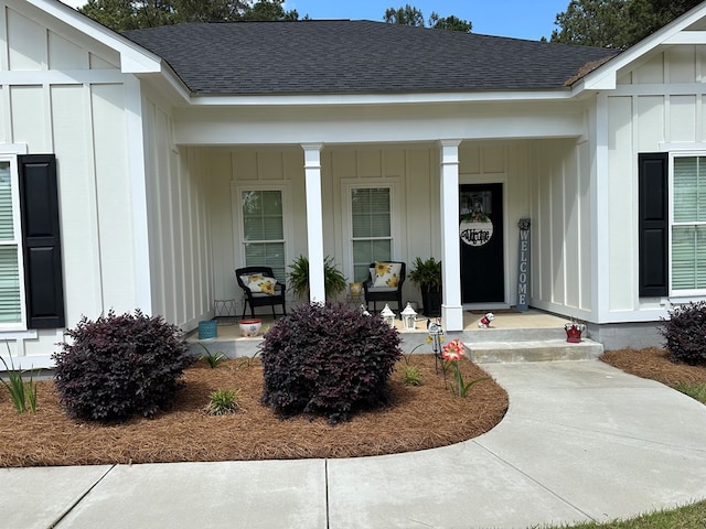 doorway to property with roof with shingles, covered porch, and board and batten siding