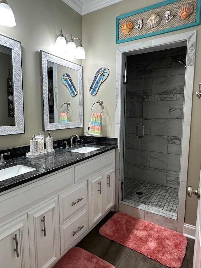 bathroom with wood finished floors, ornamental molding, a sink, and a stall shower