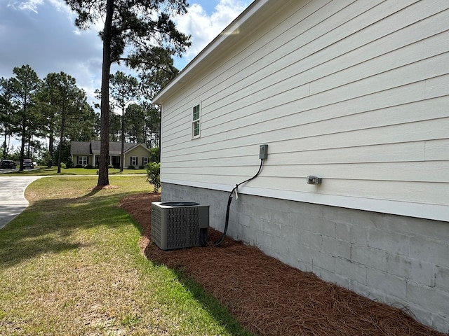 view of side of home featuring a yard and central AC