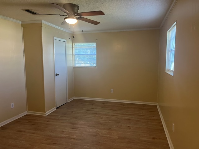 unfurnished bedroom featuring baseboards, ceiling fan, a textured ceiling, crown molding, and wood finished floors