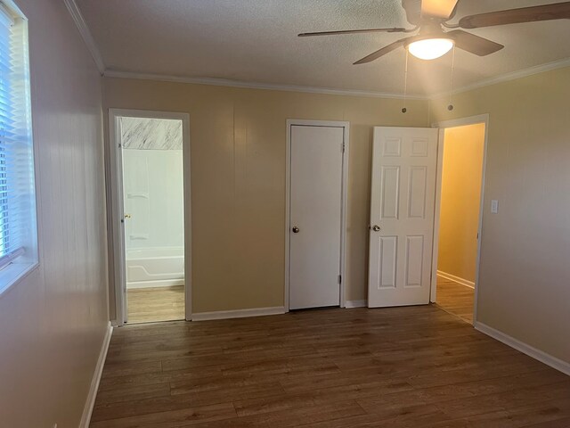 unfurnished bedroom featuring crown molding, wood finished floors, ensuite bath, and baseboards