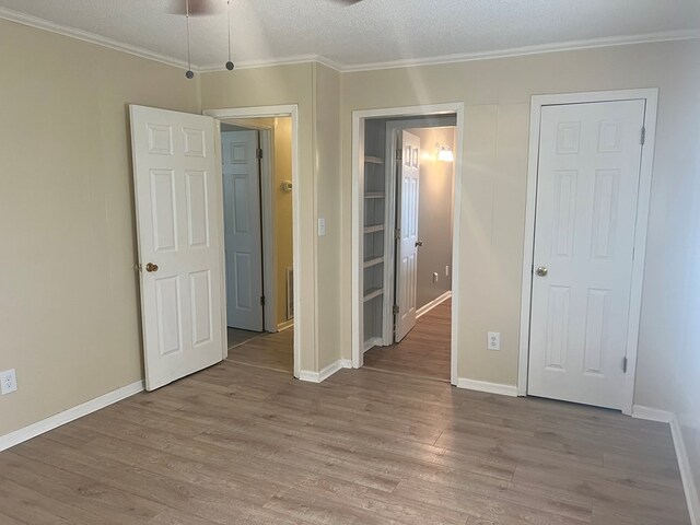 unfurnished bedroom with crown molding, baseboards, light wood-style floors, and a textured ceiling