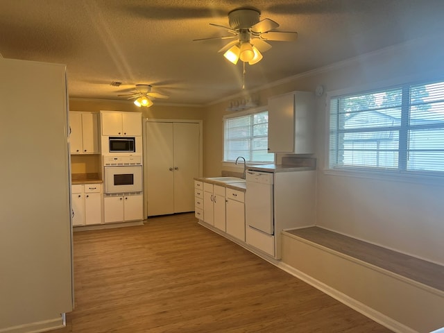 kitchen featuring ceiling fan, white appliances, light wood-type flooring, white cabinets, and a sink