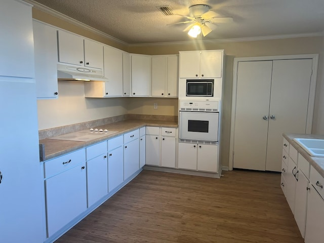 kitchen with visible vents, dark wood-style flooring, ornamental molding, white appliances, and under cabinet range hood