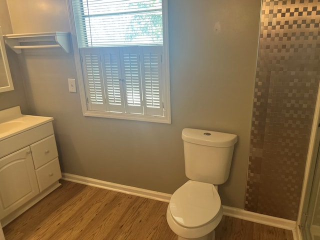full bath featuring vanity, baseboards, a stall shower, toilet, and wood finished floors