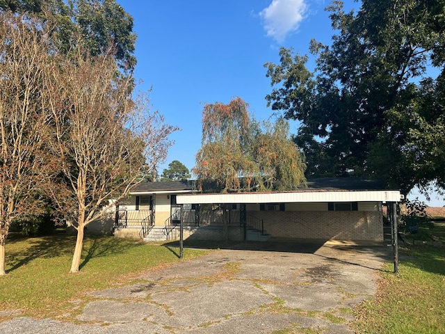 exterior space with brick siding, a front lawn, an attached carport, and concrete driveway