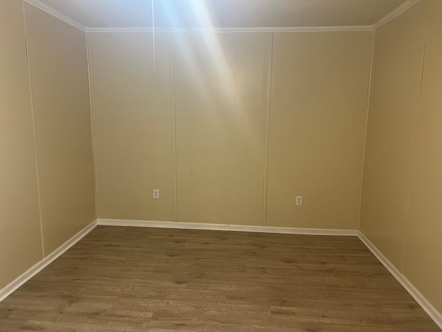 unfurnished room with crown molding, wood finished floors, and a decorative wall