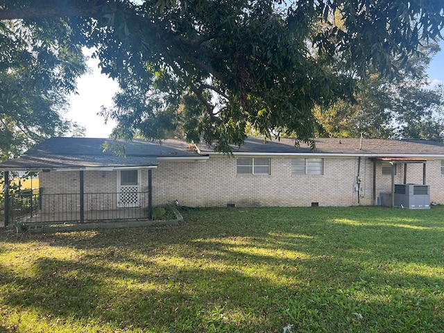 back of property featuring crawl space, a yard, central air condition unit, and brick siding