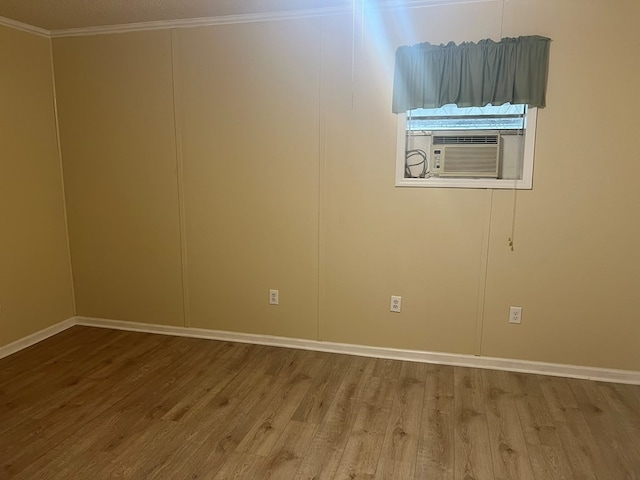 spare room featuring cooling unit, crown molding, and wood finished floors