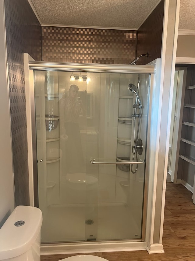 bathroom with a shower stall, a textured ceiling, toilet, and wood finished floors