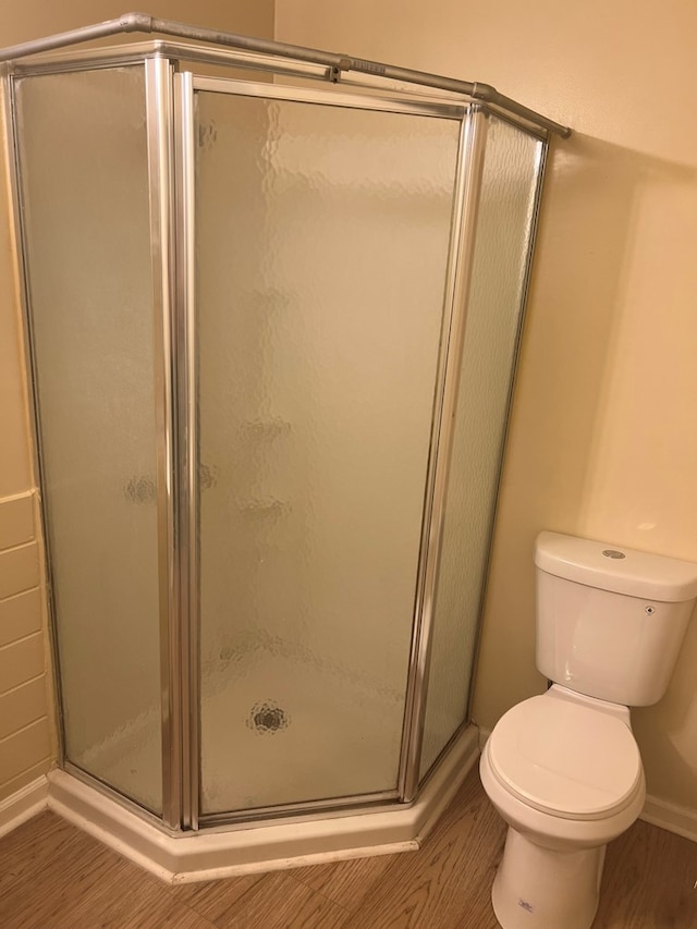 full bath with a shower stall, toilet, and wood finished floors