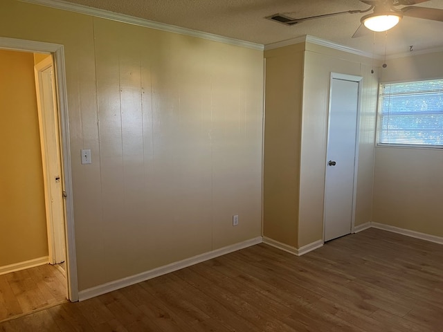 unfurnished bedroom featuring crown molding, ceiling fan, a textured ceiling, wood finished floors, and baseboards