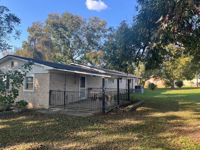 back of property featuring a yard, brick siding, a carport, and a patio
