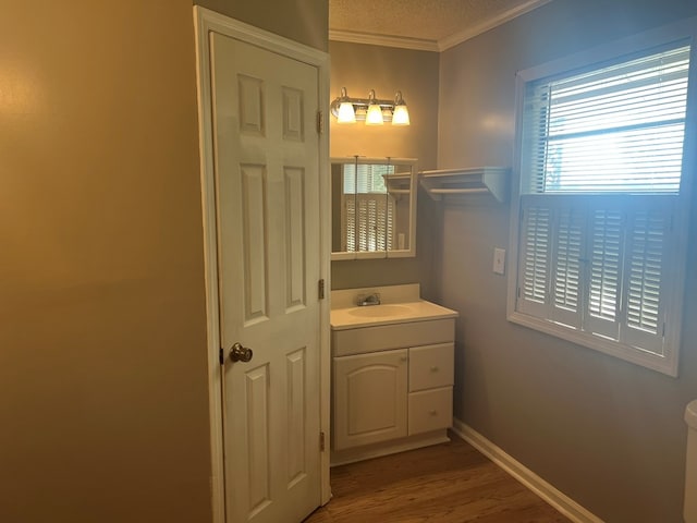 bathroom featuring vanity, baseboards, a textured ceiling, crown molding, and wood finished floors