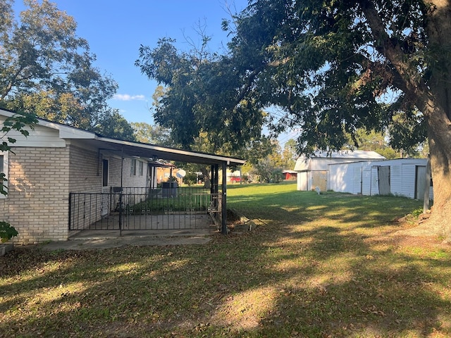 view of yard featuring a carport, an outbuilding, and a patio area