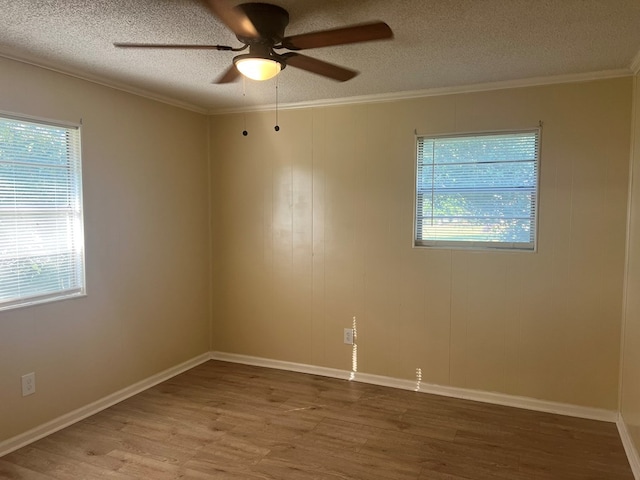 empty room featuring a ceiling fan, crown molding, and wood finished floors