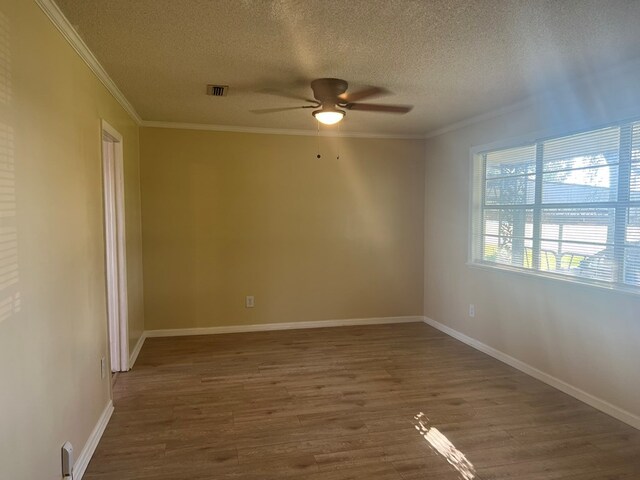 spare room with visible vents, ornamental molding, a ceiling fan, a textured ceiling, and wood finished floors
